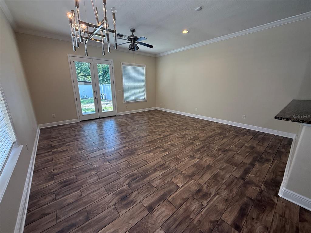 A living room features wood-look tile flooring, a modern chandelier, a ceiling fan, and French doors — 2618 E CENTRAL BOULEVARD, ORLANDO, FL
