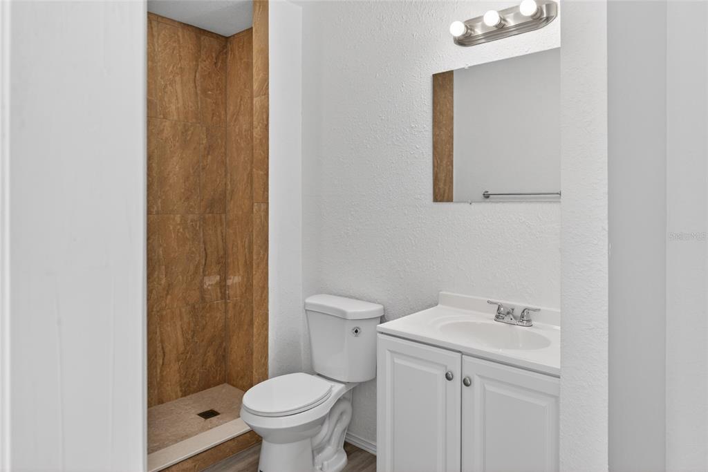 A bathroom featuring a walk-in shower with brown tile, a white toilet, and a vanity — 536 ROYAL PALM DRIVE, KISSIMMEE, FL