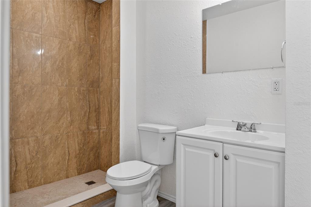 A bathroom featuring a walk-in shower with brown tile, a white toilet, and a vanity — 536 ROYAL PALM DRIVE, KISSIMMEE, FL