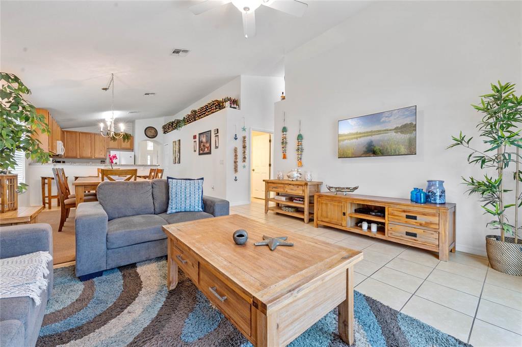 A living room features a grey sofa, wooden coffee table, media console, and tile flooring — 2509 DHARMA CIRCLE, KISSIMMEE, FL