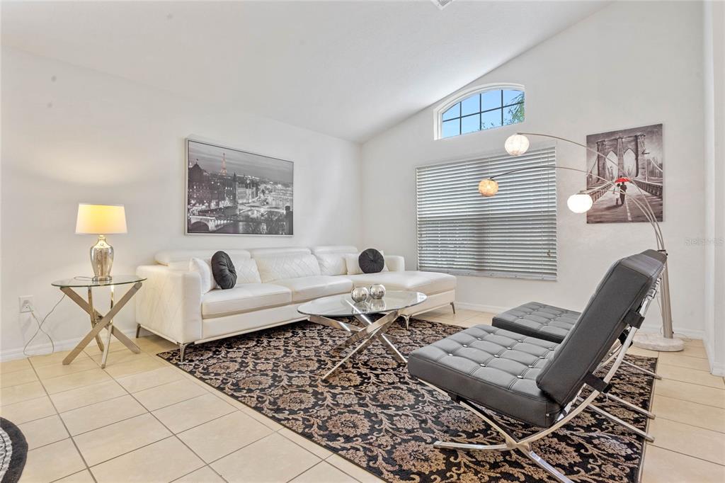 A living room features a white sectional sofa, two black chairs, and a patterned rug — 2509 DHARMA CIRCLE, KISSIMMEE, FL