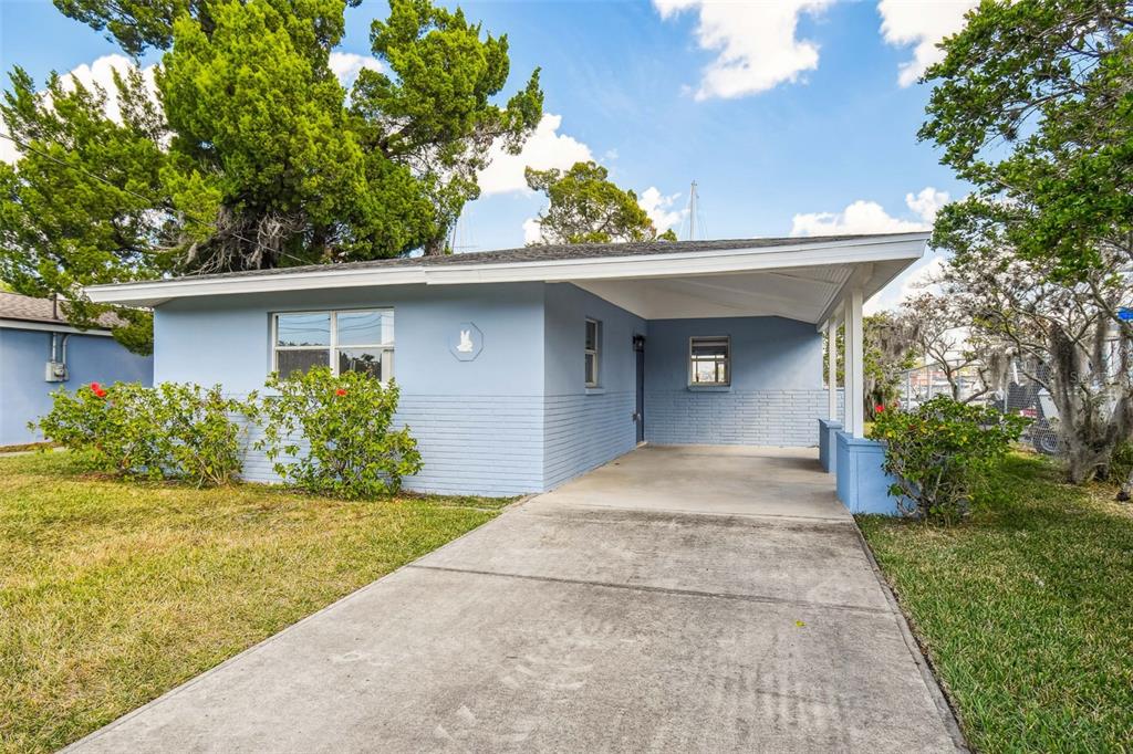 A light blue single-story house features a concrete driveway and an attached carport — 4911 FLORAMAR TERRACE, NEW PORT RICHEY, FL