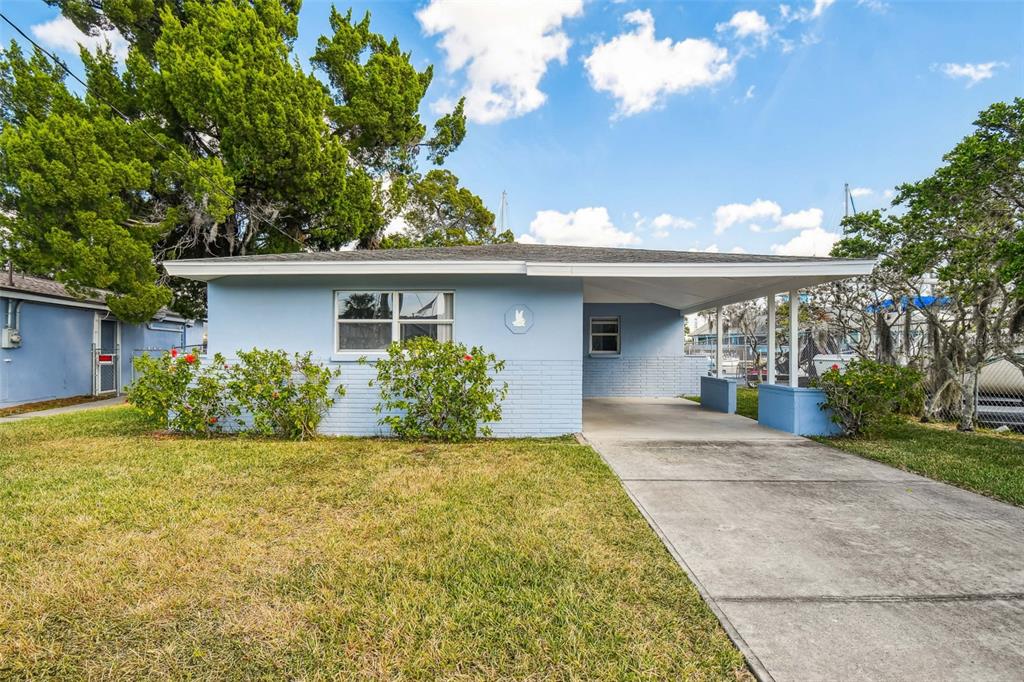 A light blue, single-story house with a concrete driveway and an attached carport — 4911 FLORAMAR TERRACE, NEW PORT RICHEY, FL