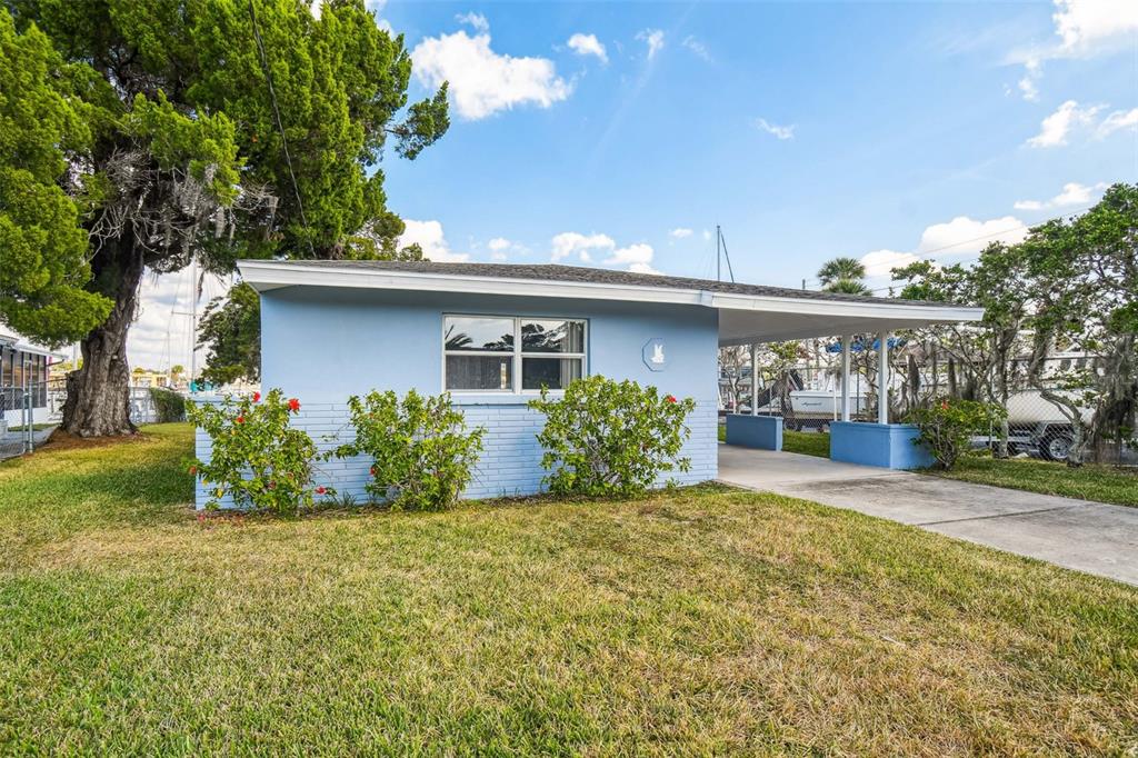 A light blue single-story house features a front carport and a grassy yard — 4911 FLORAMAR TERRACE, NEW PORT RICHEY, FL
