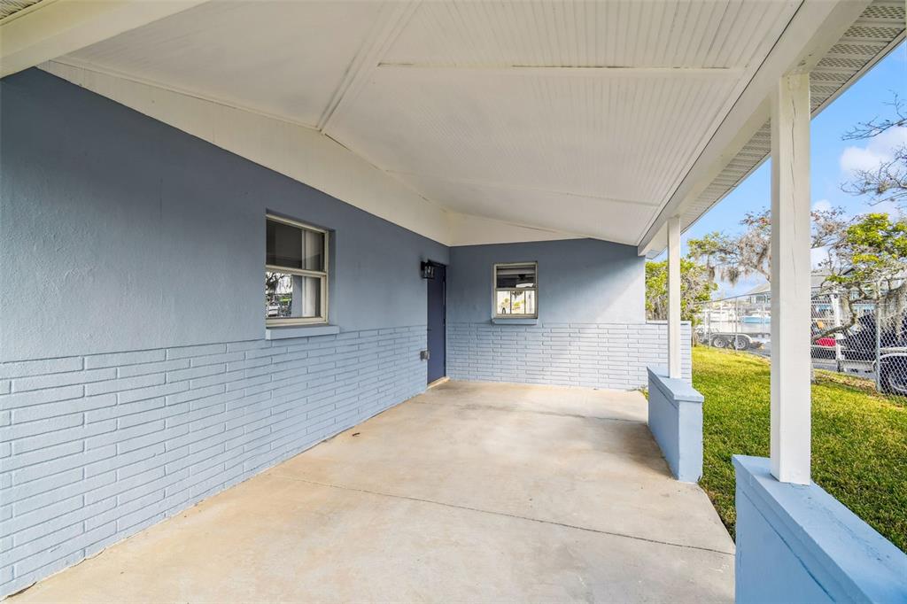 A covered concrete porch features light blue painted brick walls and a white ceiling — 4911 FLORAMAR TERRACE, NEW PORT RICHEY, FL