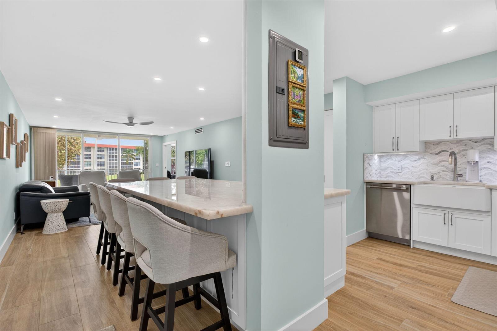 A kitchen with white cabinets and a breakfast bar overlooks a living area with balcony — 3100 NE 48th Court # 214, Lighthouse Point FL 33064, LIGHTHOUSE POINT, FL