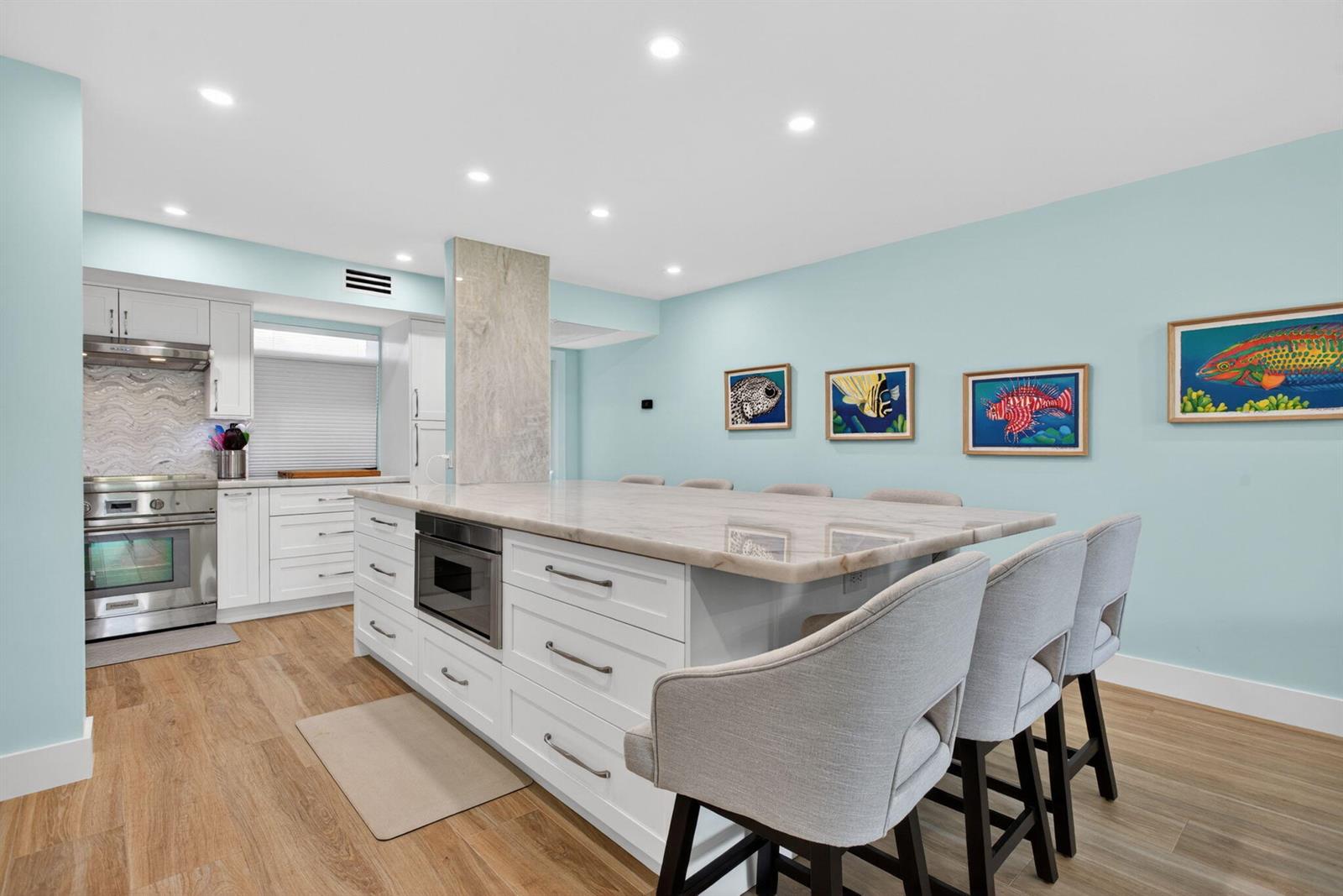 A kitchen features a large white island with a stone countertop and light blue walls — 3100 NE 48th Court # 214, Lighthouse Point FL 33064, LIGHTHOUSE POINT, FL