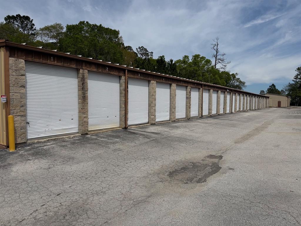 A long row of storage units with white roll-up doors and stone pillars — 2150/2160 NE 31ST AVENUE, GAINESVILLE, FL