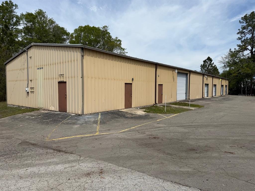 A long, tan metal industrial building with multiple doors and a roll-up garage door — 2150/2160 NE 31ST AVENUE, GAINESVILLE, FL