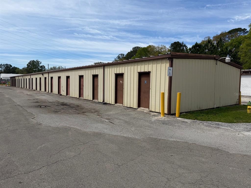 A long, single-story metal storage building with multiple brown doors sits on an asphalt lot — 2150/2160 NE 31ST AVENUE, GAINESVILLE, FL