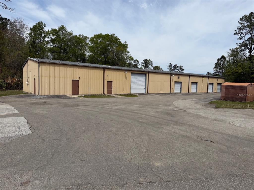 A long, single-story metal industrial building with multiple roll-up doors and entry doors — 2150/2160 NE 31ST AVENUE, GAINESVILLE, FL