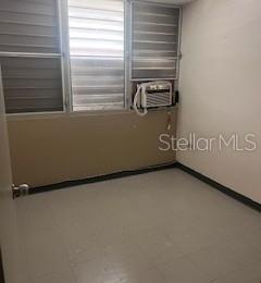 An empty room with light-colored tile flooring, beige walls, and a window air conditioning unit — B 1304 COND. TORRES DE CERVANTES UNIT 1, SAN JUAN, PR