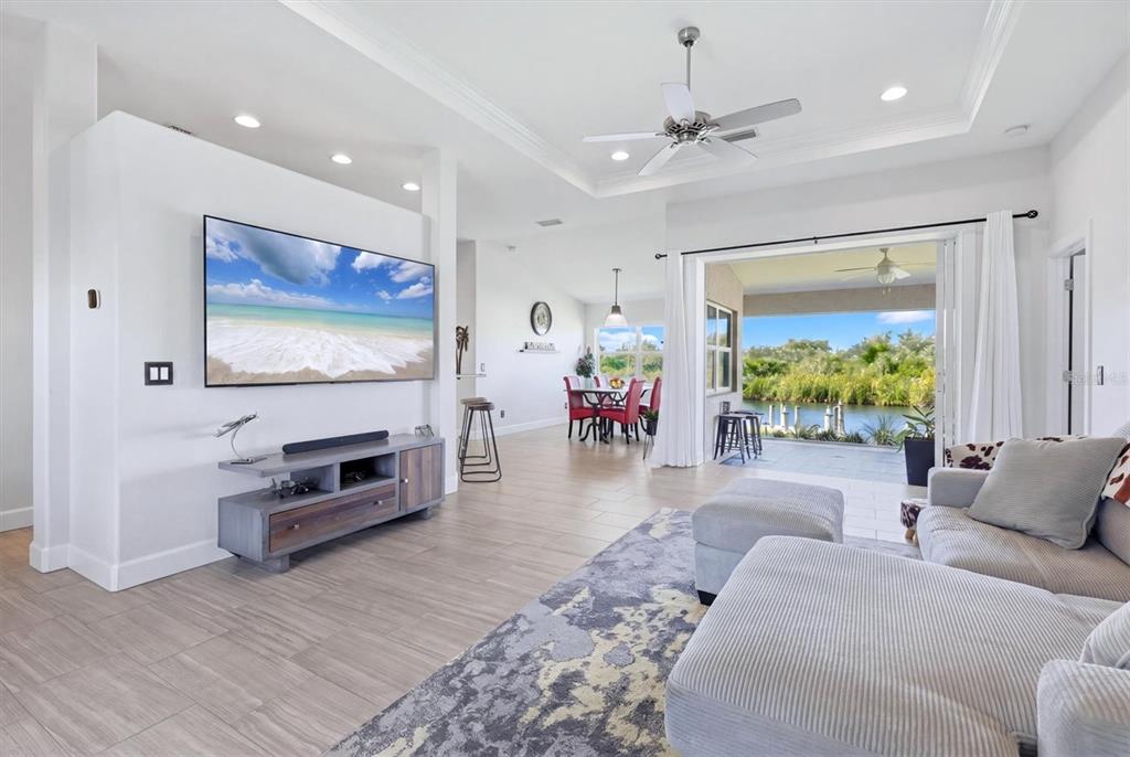 A living room with a large television, sectional sofa, and sliding doors opening to a patio — 15738 APPLEWHITE CIRCLE, PORT CHARLOTTE, FL