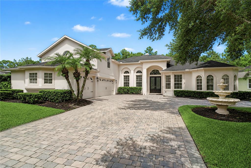 A beige house with a paved driveway, a fountain, and a two-car garage — 2710 REGAL PINE TRAIL, OVIEDO, FL