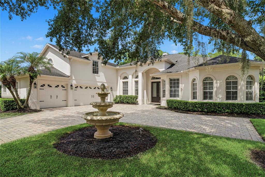 A beige house with a stone fountain in the driveway and a large oak tree — 2710 REGAL PINE TRAIL, OVIEDO, FL