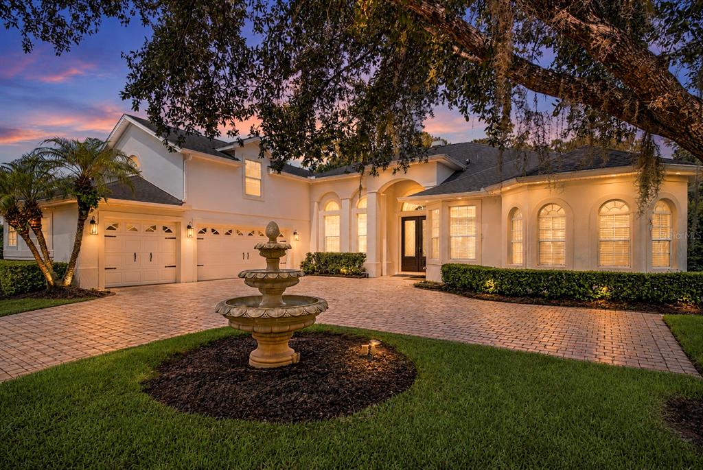A multi-story house with a brick driveway, a stone fountain, and a large oak tree — 2710 REGAL PINE TRAIL, OVIEDO, FL