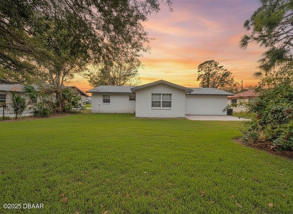 A white single-story house sits behind a large green lawn at sunset — 1022 4TH STREET, PORT ORANGE, FL