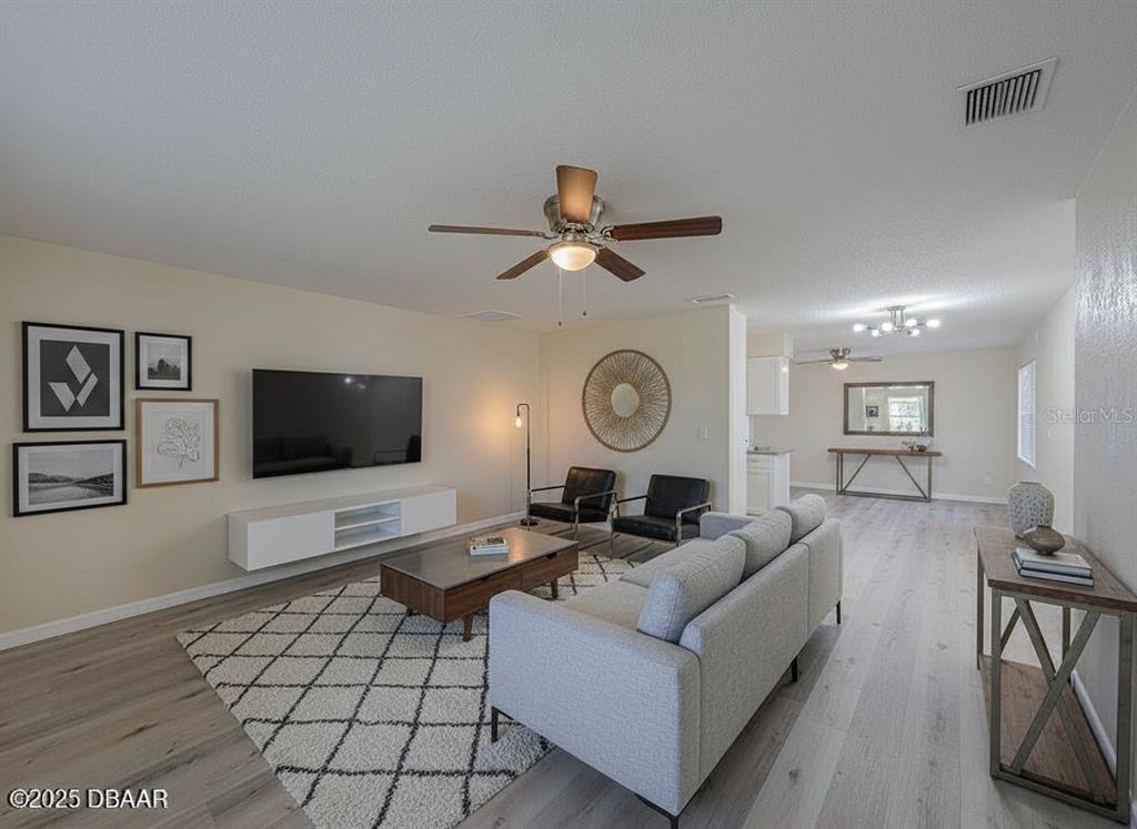 A living room features light wood flooring, a grey sofa, and a wall-mounted television — 1022 4TH STREET, PORT ORANGE, FL