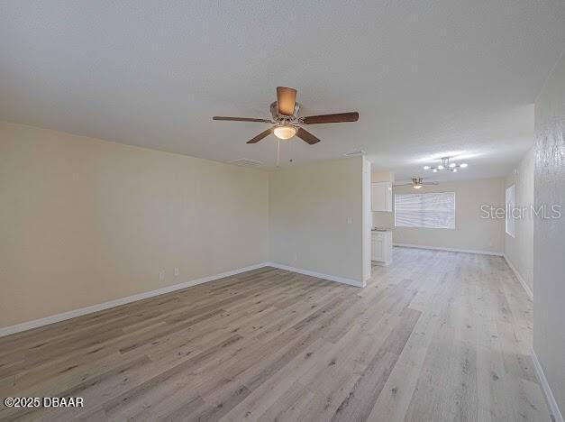 An open-concept living area features light wood-look flooring, neutral walls, and two ceiling fans — 1022 4TH STREET, PORT ORANGE, FL