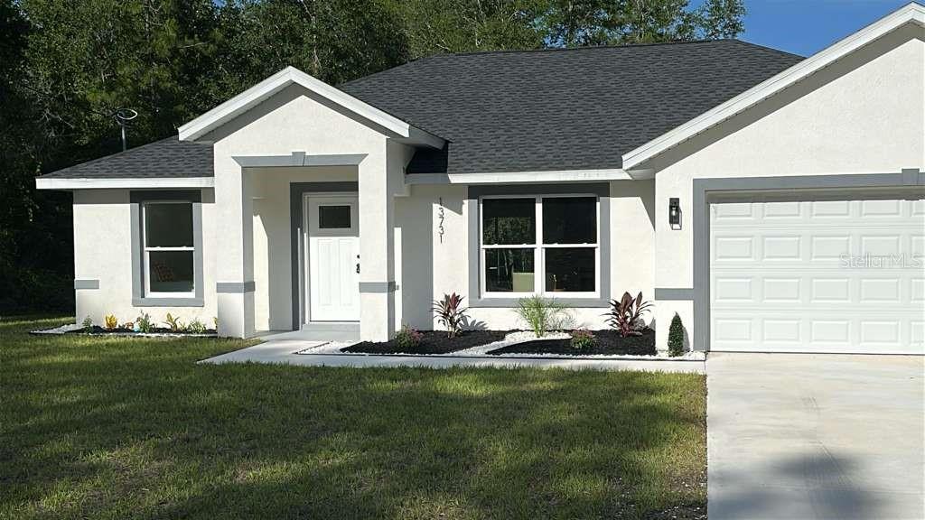 A single-story house with a white stucco exterior, gray trim, and a dark shingled roof — 13731 SW 89TH CIRCLE, OCALA, FL