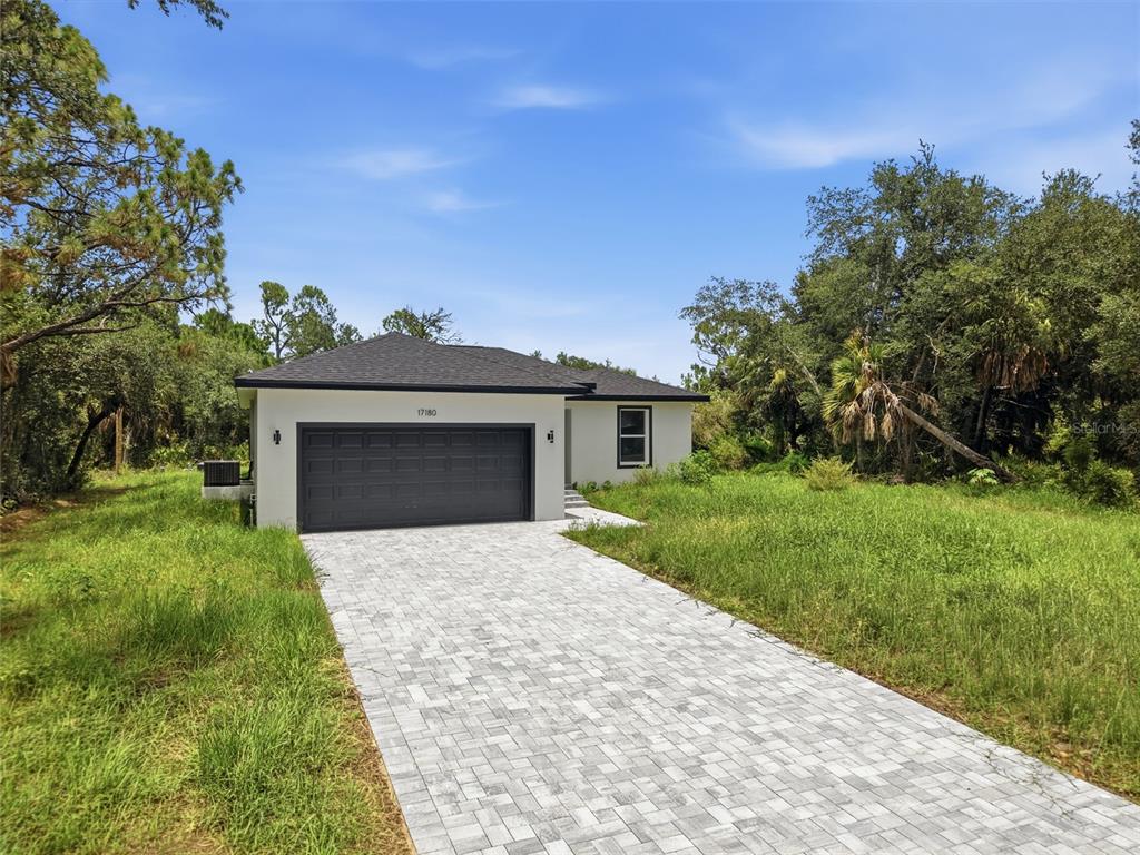 A single-story house with a dark garage door and a paved driveway sits on a lot — 17180 DRAYTON LANE, PORT CHARLOTTE, FL