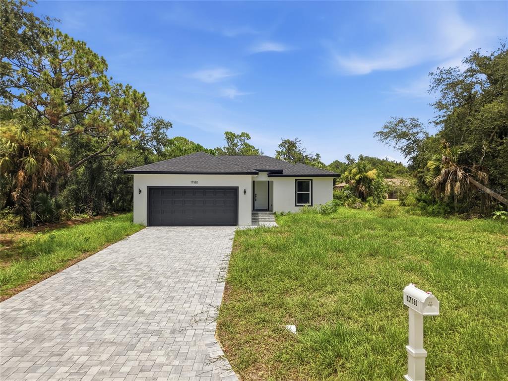 A single-story house with a paved driveway and white exterior sits on a grassy lot — 17180 DRAYTON LANE, PORT CHARLOTTE, FL