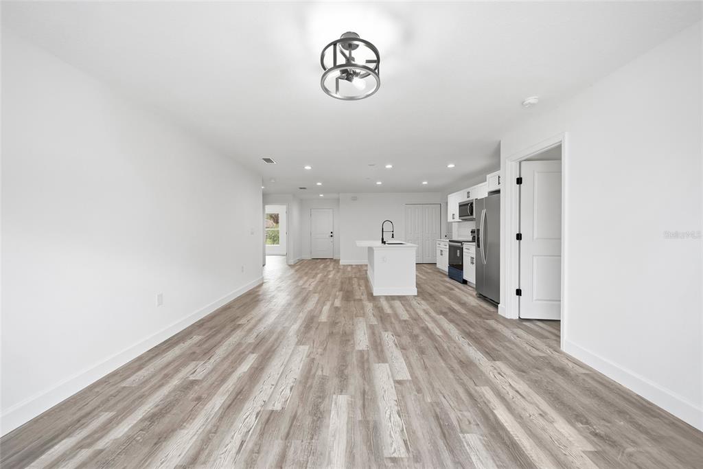 An open-concept kitchen and living area features white cabinetry, a center island, and wood-look flooring — 17180 DRAYTON LANE, PORT CHARLOTTE, FL