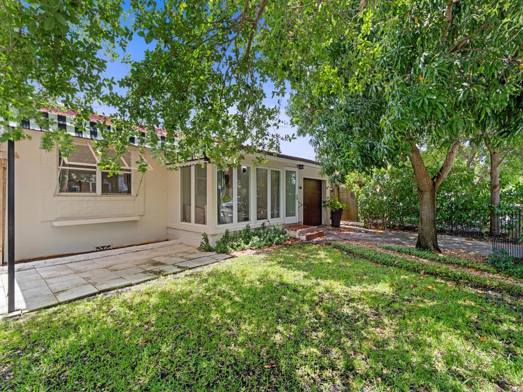 A single-story house with a white exterior, large windows, and a paved patio area — 1615 N Lakeside Drive, FL 33460, FL