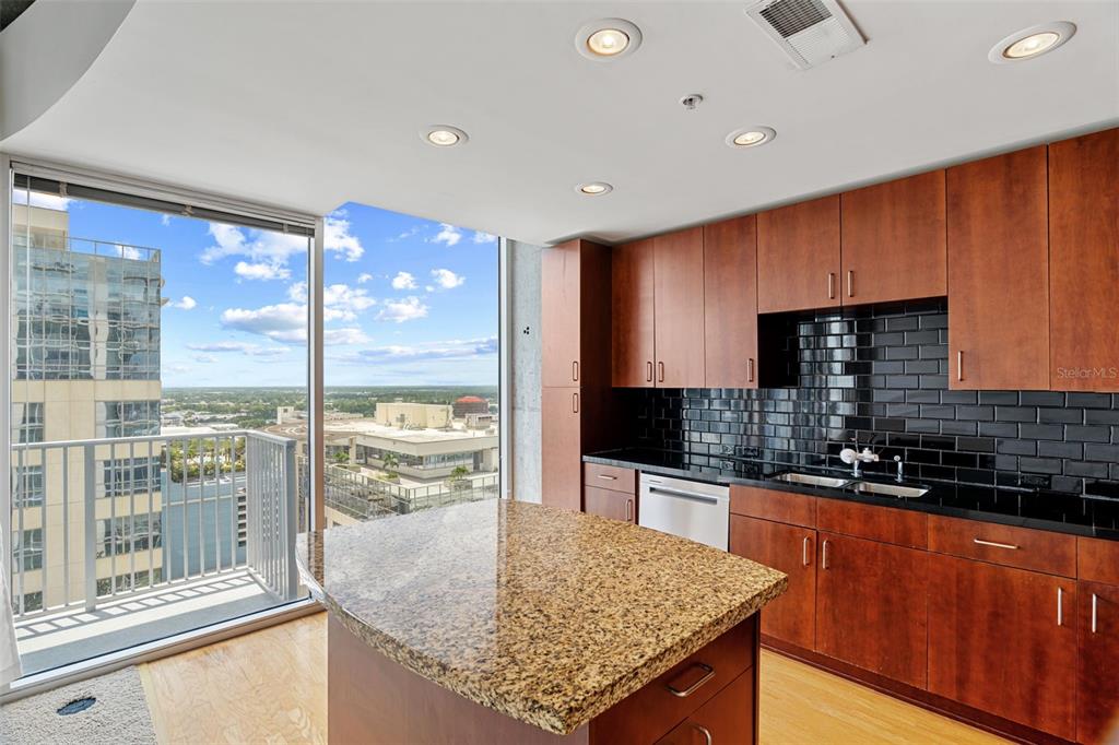 A kitchen with wood cabinets, granite countertops, and a balcony overlooking a city skyline — 155 S COURT AVENUE UNIT 2008, ORLANDO, FL