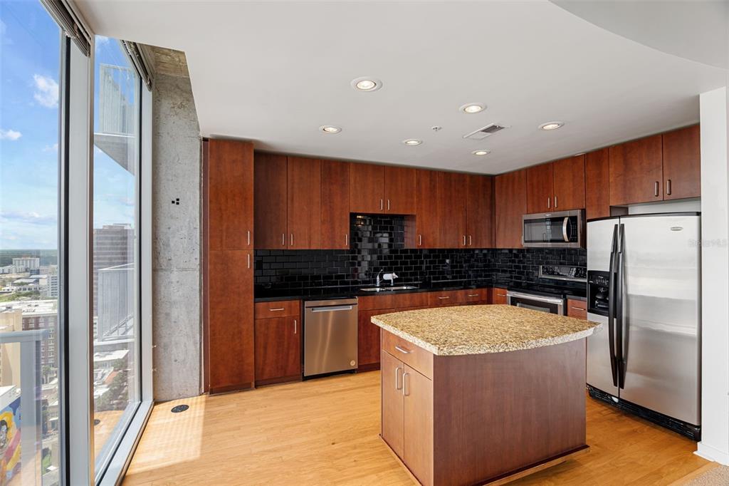 A kitchen with wood cabinets, granite countertops, stainless steel appliances, and floor-to-ceiling windows — 155 S COURT AVENUE UNIT 2008, ORLANDO, FL