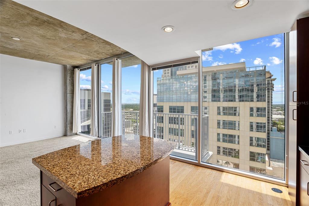 A kitchen island with granite countertops sits in a room featuring floor-to-ceiling windows and views — 155 S COURT AVENUE UNIT 2008, ORLANDO, FL