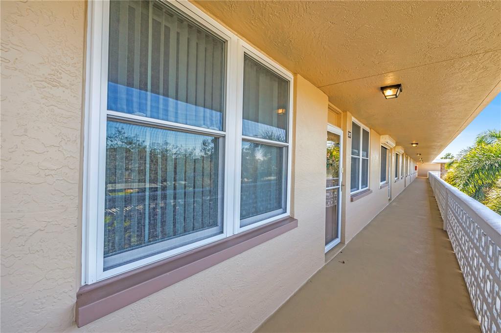An exterior walkway with a white railing runs along the side of a tan building — 5095 BAY STREET NE UNIT 317, ST PETERSBURG, FL