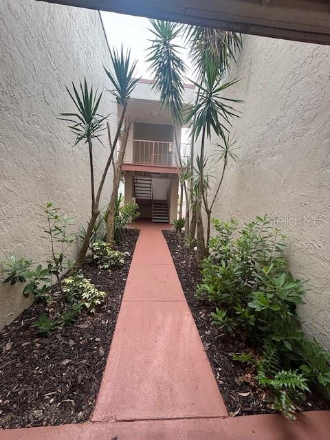 A narrow outdoor walkway leads toward a multi-story building with stairs and tropical plants — 510 ORANGE DRIVE UNIT 20, ALTAMONTE SPRINGS, FL