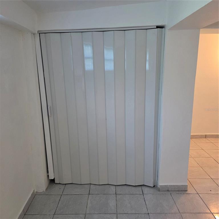 A white accordion-style folding door is installed in a room with light-colored tiled flooring — Calle Cristo Redentor CALLE CRISTO REDENTOR UNIT 57, BO. RABANAL, CIDRA, PR