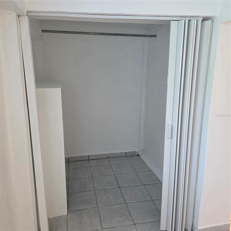A closet with a metal hanging rod, white walls, and gray tiled flooring — Calle Cristo Redentor CALLE CRISTO REDENTOR UNIT 57, BO. RABANAL, CIDRA, PR