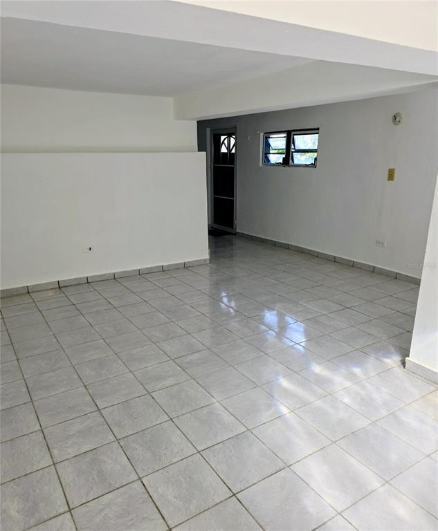An empty room features light-colored tile flooring, white walls, and a window near a doorway — Calle Cristo Redentor CALLE CRISTO REDENTOR UNIT 57, BO. RABANAL, CIDRA, PR