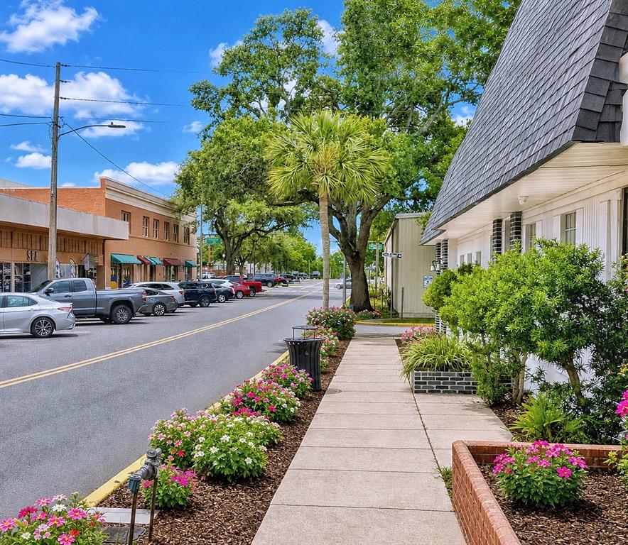 A sidewalk runs alongside a street with parked cars, trees, and storefronts in a town — 35 N 6TH STREET UNIT 1, HAINES CITY, FL