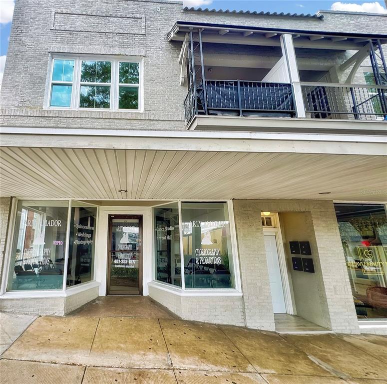A two-story brick building features a ground-level storefront with large windows and a balcony above — 35 N 6TH STREET UNIT 1, HAINES CITY, FL