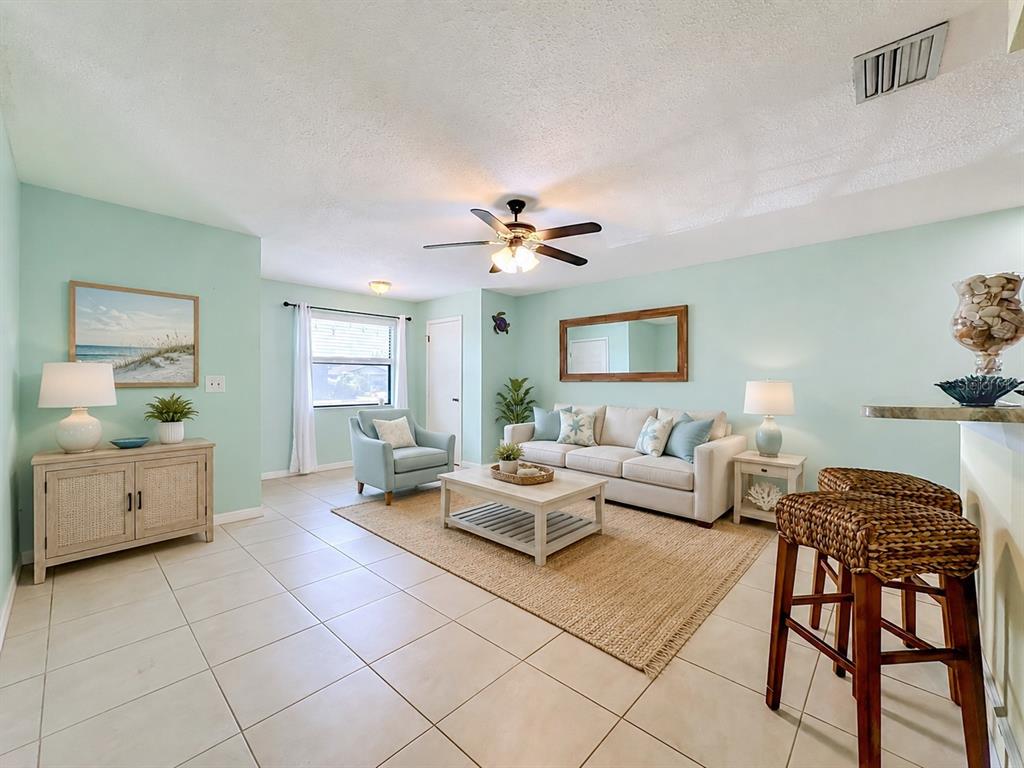 A living room features light green walls, tile flooring, a beige sofa, and a ceiling fan — 4190 66TH STREET CIRCLE W UNIT O, BRADENTON, FL
