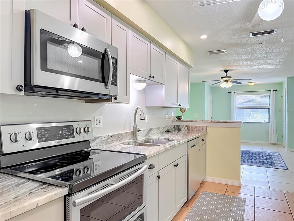 A kitchen features light-colored cabinets, stainless steel appliances, and marble-patterned countertops — 4190 66TH STREET CIRCLE W UNIT O, BRADENTON, FL