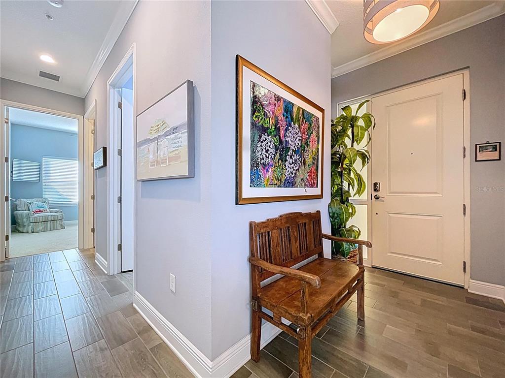 An entryway features a wooden bench, framed artwork, and a white door with sidelights — 7730 34TH AVE W UNIT 303, BRADENTON, FL