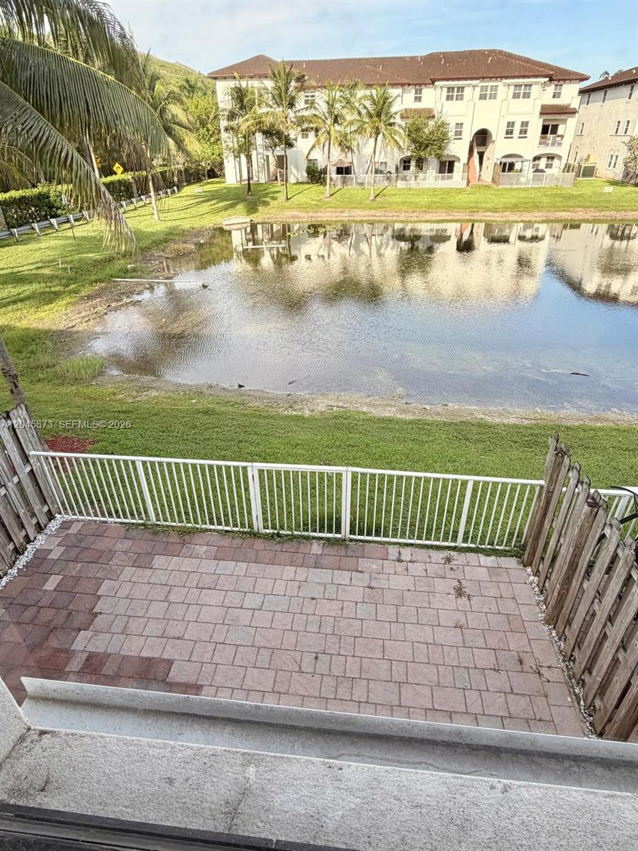 A paved patio overlooks a small pond and a multi-story apartment building — 8965 NW 98th Ave, Doral FL 33178, DORAL, FL