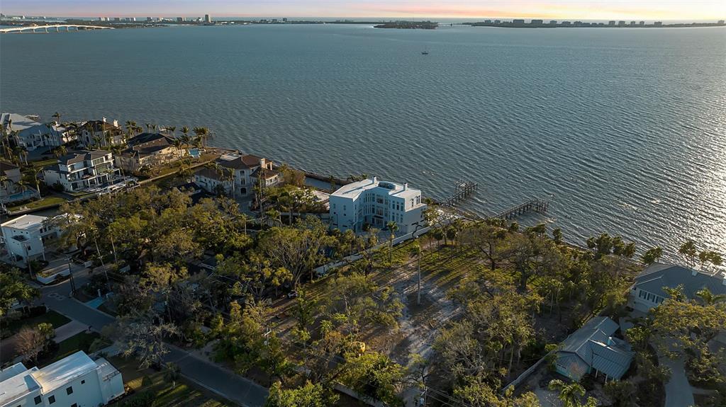 An aerial view shows a large white waterfront house surrounded by trees and a dock — 2046 ALAMEDA AVENUE, SARASOTA, FL