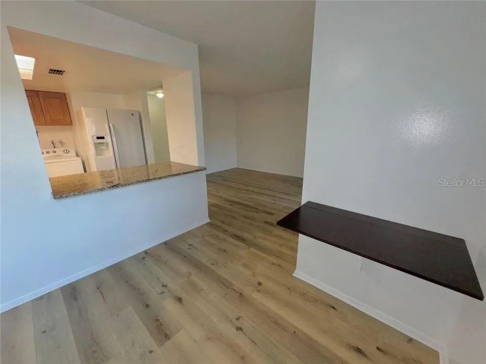 A kitchen with a breakfast bar overlooks a living area with light wood-look flooring — 9909 SWEEPSTAKES LANE UNIT 4, ORLANDO, FL