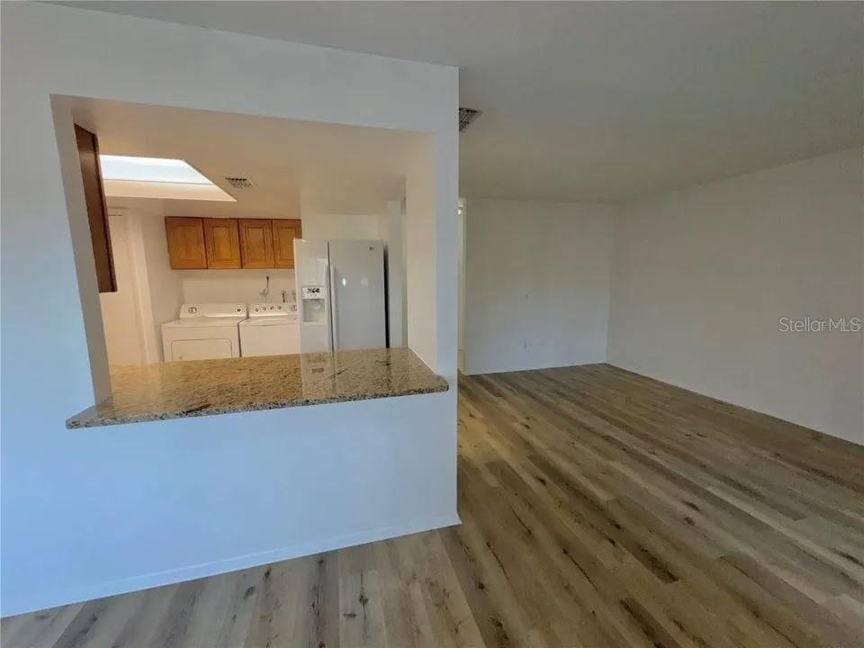 A view from a living area looking into a kitchen with a granite breakfast bar — 9909 SWEEPSTAKES LANE UNIT 4, ORLANDO, FL