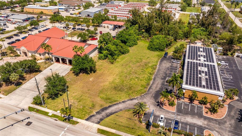 An aerial view shows a vacant grassy lot situated between two commercial buildings with parking — 1500 TAMIAMI TRAIL, PUNTA GORDA, FL