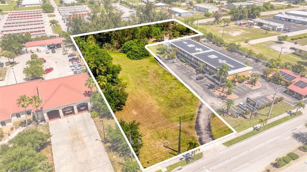 An aerial view shows a vacant, grassy lot situated between a commercial building and a fire station — 1500 TAMIAMI TRAIL, PUNTA GORDA, FL