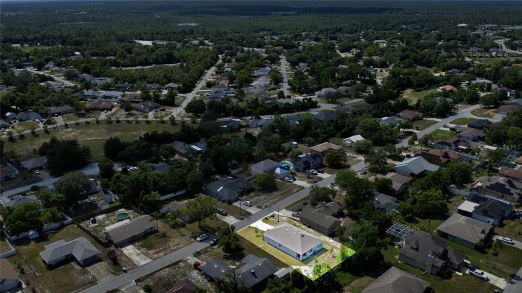 An aerial view shows a single-story house with a light-colored roof in a suburban neighborhood — 2033 E GLORIA DRIVE, DELTONA, FL