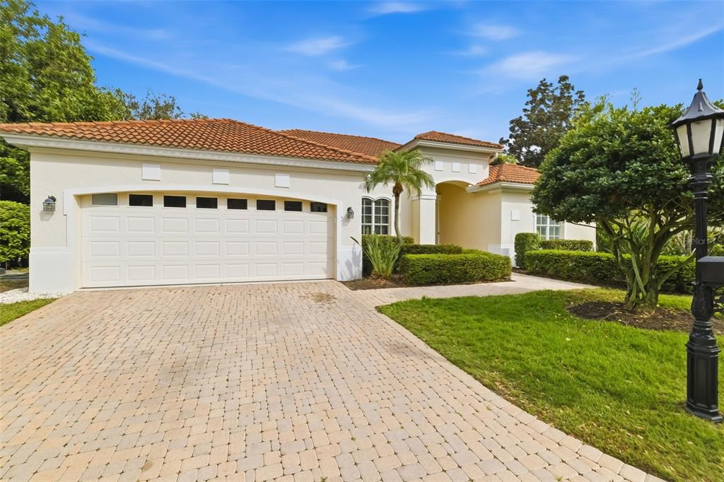 A single-story house with a beige stucco exterior, a tiled roof, and a paved driveway — 7418 MONTE VERDE, SARASOTA, FL
