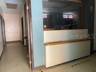 An interior view shows a hallway leading to a reception desk with a glass partition — 26 CORCHADO, AGUADILLA, PR